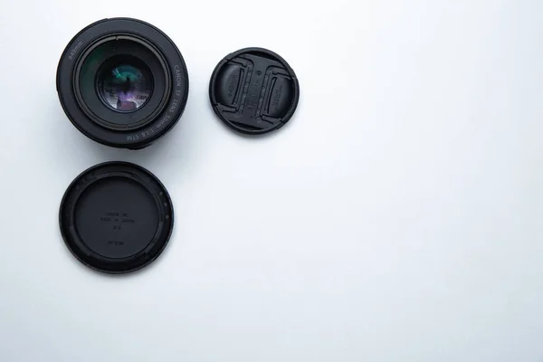 Uma pequena lente fixa para uma câmera profissional em um fundo branco com duas tampas. — Fotografia de Stock