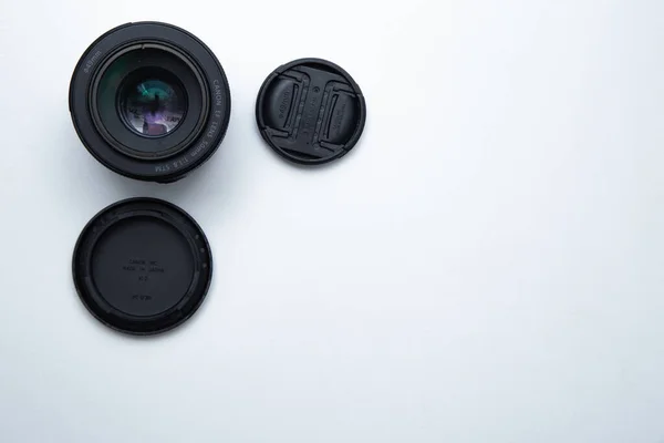 Een kleine vaste lens voor een professionele camera op een witte achtergrond met twee hoezen. — Stockfoto