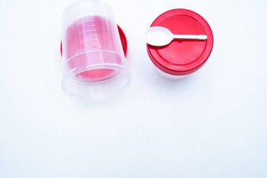 Kırmızı kapaklı ve beyaz arka planda kaşığı olan testler için kavanozlar.. 