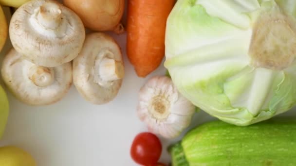 Groenten en porcini champignons draaien langzaam op een witte achtergrond. — Stockvideo