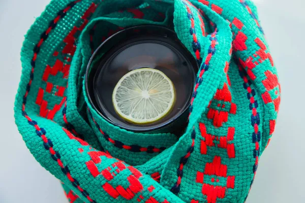 Yeşil ve kırmızı eşarba sarılmış limonlu bir fincan çay.. 