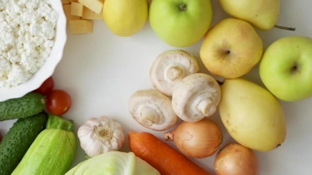 En hand sätter en körsbärstomat på en bakgrund av grönsaker, frukt, porcini svamp och mejeriprodukter. — Stockvideo