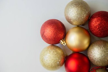 Altın ve kırmızı Noel topları, pullu ve pulsuz beyaz arka planda yatar..