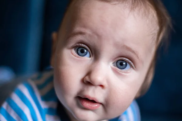 Un niño con grandes ojos azules mira a la cámara con sorpresa, un primer plano de su cara. — Foto de Stock