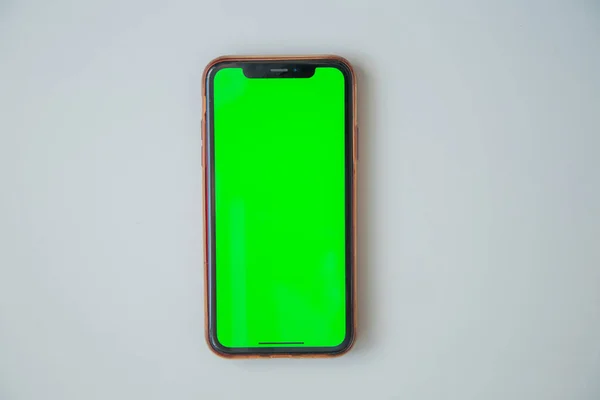 Telefon se zelenou obrazovkou je na bílém pozadí. — Stock fotografie