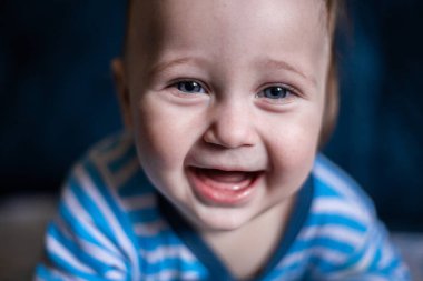 Çizgili bluz giymiş gülümseyen dişsiz bir çocuk gülüyor.. 