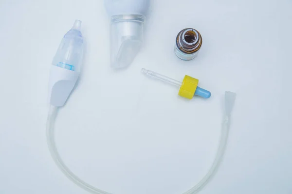 L'aspiratore da bambini si trova in un semicerchio su uno sfondo bianco, sul lato di esso sono gocce da un naso che cola con una pipetta e acqua per il lavaggio.. — Foto Stock