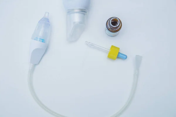 Çocuk aspiratörü beyaz bir arka planda yarı daire şeklinde uzanır, yan tarafında pipetli ve yıkanmak için suyu olan bir burundan damlalar vardır..