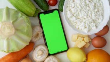 Krom anahtarlı telefon yemeğin arasında duruyor ve el ekranda tıkırtılar yapıyor.. 