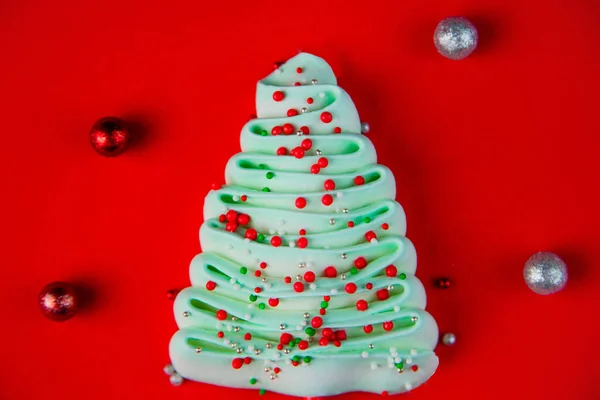 Turkuaz bizet Noel ağacı, parlak kırmızı arka planda renkli toz toplarıyla süslenmiş.