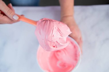 Pembe kremalı marangoz, beyaz mermer arka planda beyaz bir kasede bir pasta şefinin elleriyle karıştırılır.