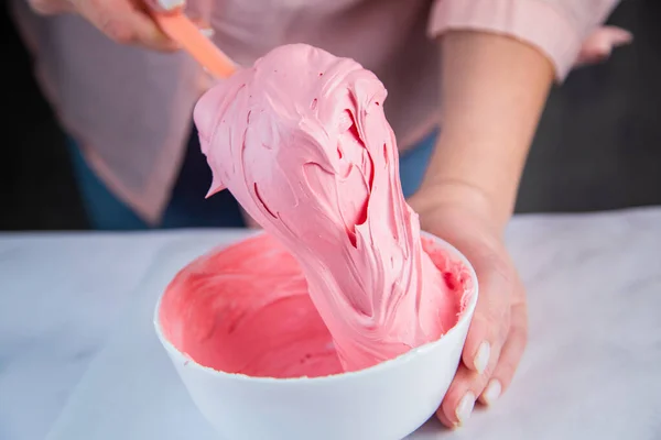 Pink confectionary meringue marengo is mixed in a white bowl on a white marble background by the hands of a pastry chef — Fotografia de Stock