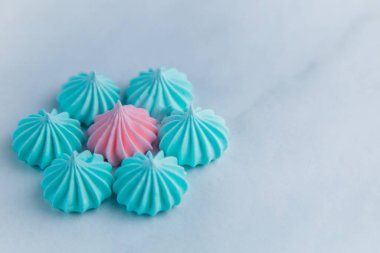 Turkuaz yapraklı bir çiçek ve kremadan yapılmış pembe bir çekirdek açık mermer bir arka planda yer alır.