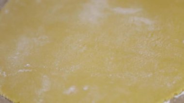 Merdane hamurun üzerine yuvarlanır, un serpilir ve rulo haline getirilir. Video yakın plan ve koyu tuşa basılı