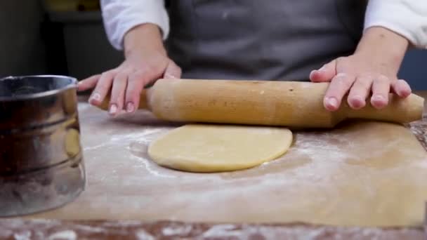 O chef de pastelaria rola a massa com um rolo, em seguida, levanta o círculo rolado, polvilha farinha no pergaminho e rola-lo novamente. — Vídeo de Stock