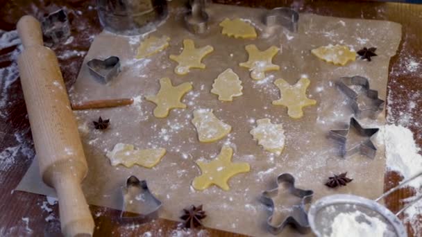 여러 가지 모양의 반죽을 만들어 낸 쿠키 를 양피지에 뿌리고 가루를 그 위에 뿌리고 곰팡이, 밀가루, 압착 핀 을 옆에서 볼 수있다. 어두운 열쇠로 찍은 비디오 — 비디오