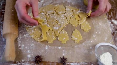  Yuvarlanan hamurun üzerinde, aşçı kurabiyeleri Noel ağacı şeklinde keser ve fazla hamuru ortadan kaldırır.