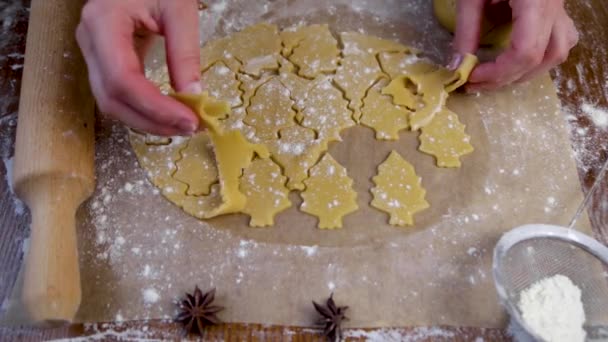 Na massa enrolada, o cozinheiro corta biscoitos com um cortador de biscoitos na forma de uma árvore de Natal e remove o excesso de massa — Vídeo de Stock