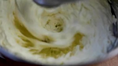 Demir karıştırıcı, mutfakta bej rengi pasta için krem şanti yapıyor.