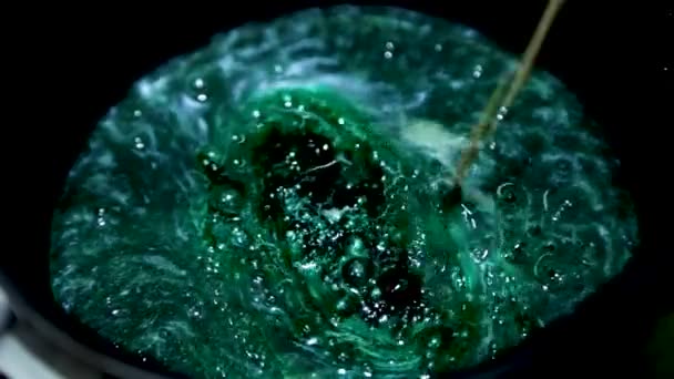 Et grønt brygg brygges i en kasserolle, som røres med en trestokk og begynner å skum med hvite bobler. Produksjon av rosa karamell – stockvideo