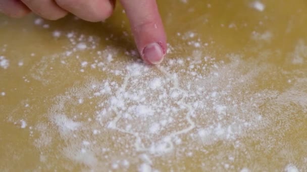Ciasto pokazuje choinkę wyciętą pleśnią, która była posypana mąką na wierzchu, kucharz rysuje wzór jak girlanda na palcu.. — Wideo stockowe