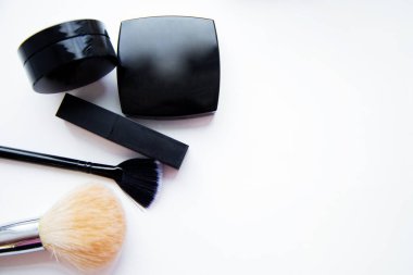 Ruj ve yüz pudrası ve fırçası yazı için yeri olan beyaz arkaplanda yan yana yatıyor