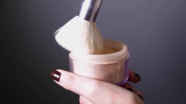 Bir fırça gri bir kavanozun içine konur ve kavanoza vurur. Gri bir arka planda parıltı bulutu yaratır.