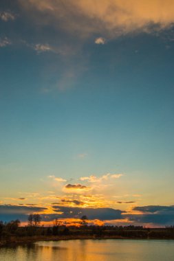 Güzel gün batımı ve gökyüzünde dramatik bulutlar. Gölün sularına yansıyor. Güzel doğal arkaplan.