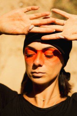 Makyajlı ve yüz sanatıyla Amerikan kabilesi ya da Orta Doğu tarzında güzel bir kadının portresi. Etnik imaj, kırmızı gözler ve siyah başörtüsü. Yakın plan..