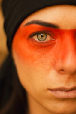 Makyajlı ve yüz sanatıyla Amerikan kabilesi ya da Orta Doğu tarzında güzel bir kadının portresi. Etnik imaj, kırmızı gözler ve siyah başörtüsü. Yakın plan..