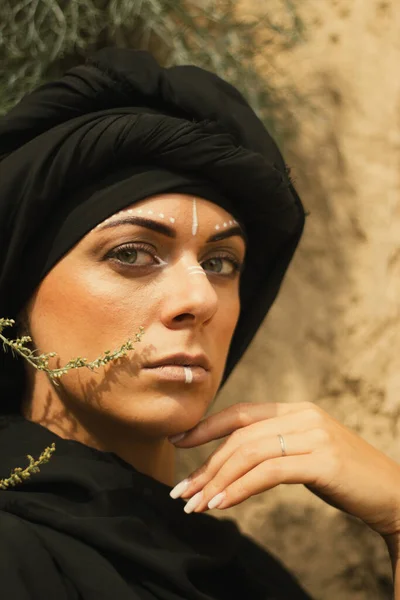 化粧をした若い美しい女性の肖像画と黒ヒジャーブを身に着けている部族や中東のスタイルで白い顔の芸術の装飾 民族的なイメージ砂の壁の背景のクローズアップ — ストック写真