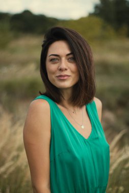 Açık havada özel dersler. Yeşil çayır üzerinde yeşil elbiseli genç esmer, yeşil tarlası olan bir köyde doğal makyajlı güzel bir kız. Doğal güneş ışığı yaz güneşli gün