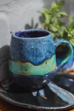 Seramik bardak koyu mavi, açık mavi ve nane renginde buruşmuş. Gri ve ahşap arka plan. Tasarımın için bir yer.