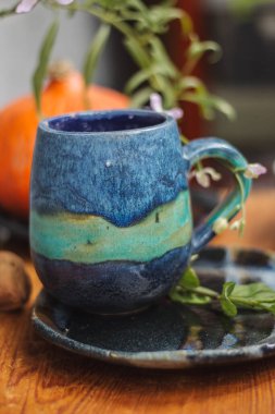 Seramik bardak koyu mavi, açık mavi ve nane renginde buruşmuş. Gri ve ahşap arka plan. Tasarımın için bir yer.