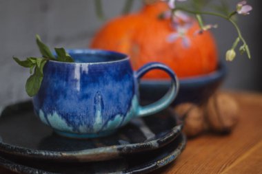 Seramik bardak koyu mavi, açık mavi ve nane renginde buruşmuş. Gri ve ahşap arka plan. Tasarımın için bir yer.