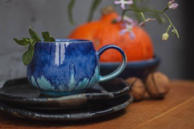 Seramik bardak koyu mavi, açık mavi ve nane renginde buruşmuş. Gri ve ahşap arka plan. Tasarımın için bir yer.