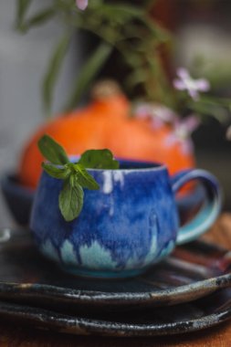 Seramik bardak koyu mavi, açık mavi ve nane renginde buruşmuş. Gri ve ahşap arka plan. Tasarımın için bir yer.