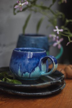 Seramik bardak koyu mavi, açık mavi ve nane renginde buruşmuş. Gri ve ahşap arka plan. Tasarımın için bir yer.