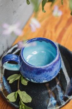 Seramik bardak koyu mavi, açık mavi ve nane renginde buruşmuş. Gri ve ahşap arka plan. Tasarımın için bir yer.