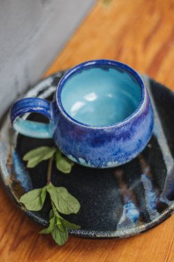 Seramik bardak koyu mavi, açık mavi ve nane renginde buruşmuş. Gri ve ahşap arka plan. Tasarımın için bir yer.