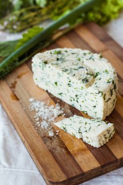 Ev yapımı organik beyaz peynir, baharatlı otlar ve ahşap bir tahtanın üzerinde tuz. Doğal ışık, güzel arkaplan ve tasarımın için yer var.