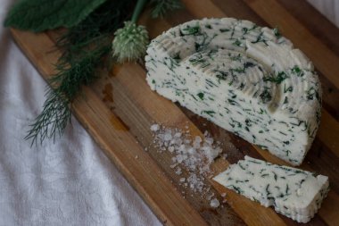 Ev yapımı organik beyaz peynir, baharatlı otlar ve ahşap bir tahtanın üzerinde tuz. Doğal ışık, güzel arkaplan ve tasarımın için yer var.