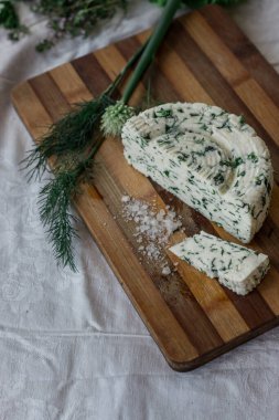 Ev yapımı organik beyaz peynir, baharatlı otlar ve ahşap bir tahtanın üzerinde tuz. Doğal ışık, güzel arkaplan ve tasarımın için yer var.