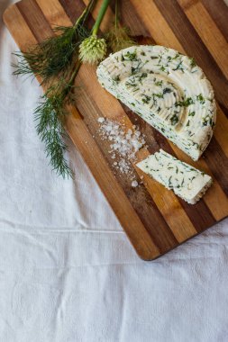 Ev yapımı organik beyaz peynir, baharatlı otlar ve ahşap bir tahtanın üzerinde tuz. Doğal ışık, güzel arkaplan ve tasarımın için yer var.