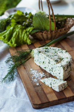 Ev yapımı organik beyaz peynir, baharatlı otlar ve ahşap bir tahtanın üzerinde tuz. Doğal ışık, güzel arkaplan ve tasarımın için yer var.