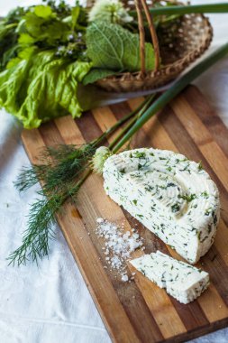 Ev yapımı organik beyaz peynir, baharatlı otlar ve ahşap bir tahtanın üzerinde tuz. Doğal ışık, güzel arkaplan ve tasarımın için yer var.
