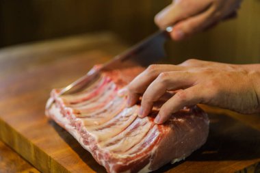 Şef çiğ et keser. Domuz pirzolası doğrayan kasap. Tahta kesme tahtasında kemikli et. Ulusal Mutfak