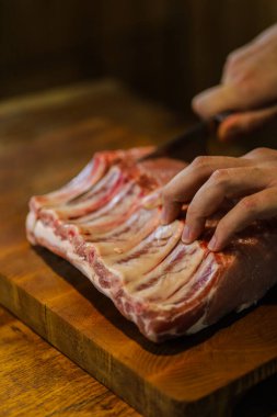 Şef çiğ et keser. Domuz pirzolası doğrayan kasap. Tahta kesme tahtasında kemikli et. Ulusal Mutfak