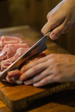 Şef çiğ et keser. Domuz pirzolası doğrayan kasap. Tahta kesme tahtasında kemikli et. Ulusal Mutfak