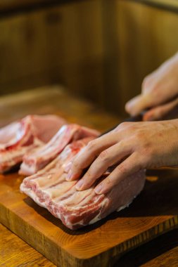 Şef çiğ et keser. Domuz pirzolası doğrayan kasap. Tahta kesme tahtasında kemikli et. Ulusal Mutfak
